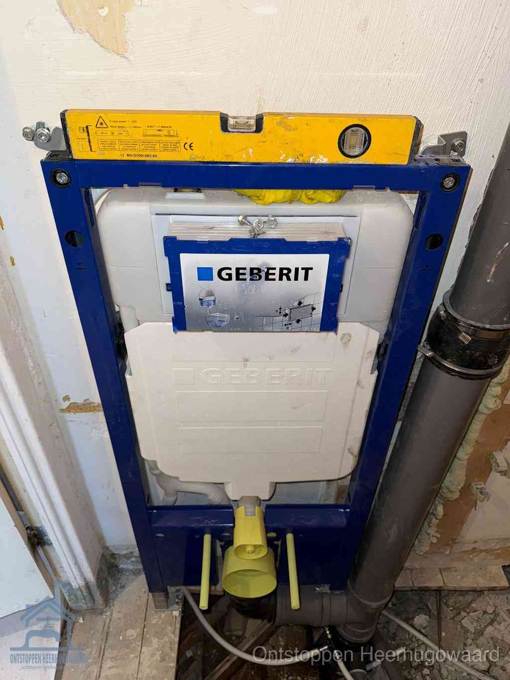 Een Geberit inbouwreservoir met frame voor een hangtoilet tegen de wand, met de afvoerbocht naar de vloer, kenmerkend voor een verstopt hangtoilet in Heerhugowaard