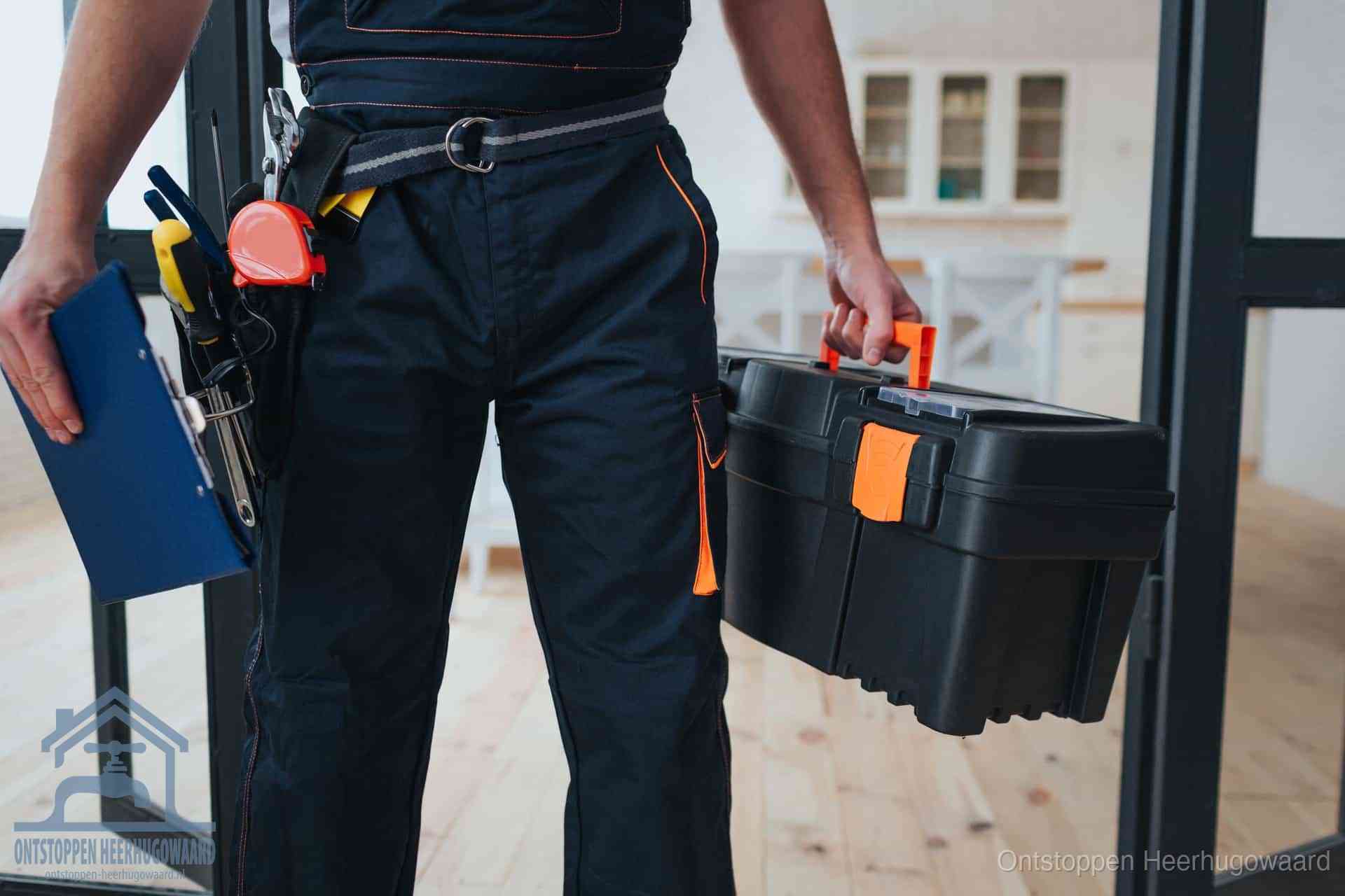 Een monteur met gereedschapsriem en klembord in een keuken, klaar om een transparante prijs voor het gootsteen ontstoppen in Heerhugowaard te geven