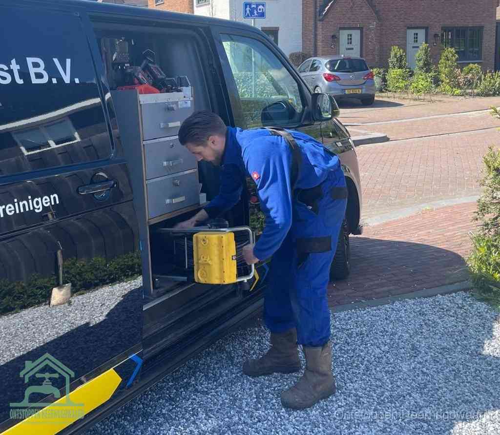 Een monteur pakt buiten op de oprit gereedschap uit de bedrijfsbus, het moment om een professional in te schakelen voor een verstopte afvoer in Heerhugowaard