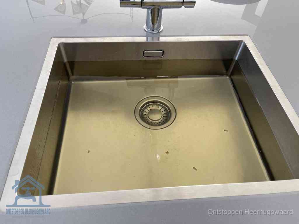 Stilstaand water in een rvs spoelbak dat niet wegloopt, een duidelijk signaal van een gootsteenverstopping in Heerhugowaard