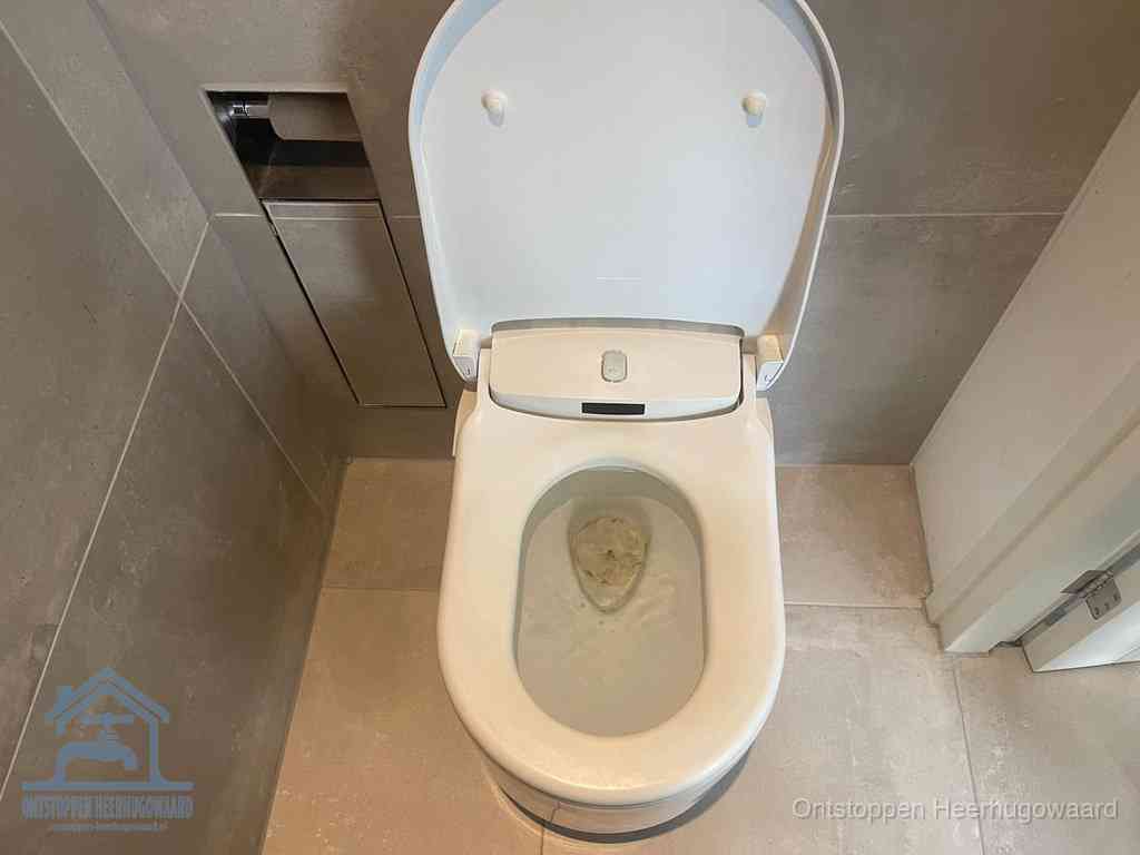 Een wit hangtoilet waarin een prop wc-papier op het water blijft drijven, een duidelijk signaal van een verstopte wc in Heerhugowaard