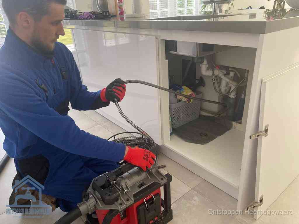 Een monteur reinigt de keukenafvoer grondig met een veermachine om terugkerende gootsteenverstoppingen te voorkomen in Heerhugowaard