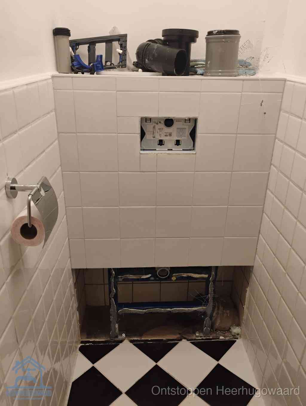 Een toiletruimte waar het hangtoilet en de inbouwreservoir-onderdelen zijn vrijgelegd voor onderhoud, periodiek nazicht voorkomt een wc-verstopping in Heerhugowaard